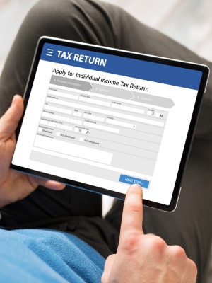 Man applying for income tax return using a tablet device at home in a comfortable setting Man applying for income tax return using a tablet device