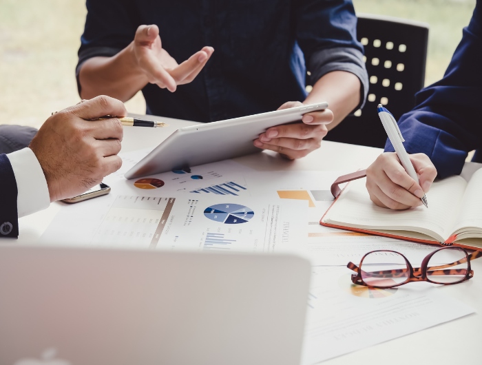 Business valuation experts analyzing financial reports and graphs during a meeting at a conference room table