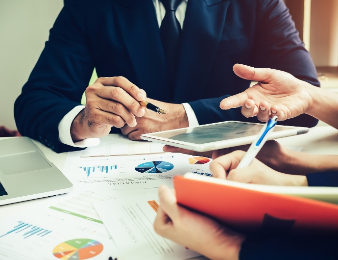 Professional team discussing business valuation strategies in a modern office setting with analytical reports and digital devices Team members collaborate on business valuation